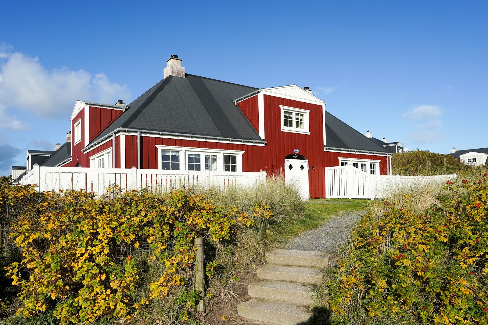 A red house with white trim and a white fence.